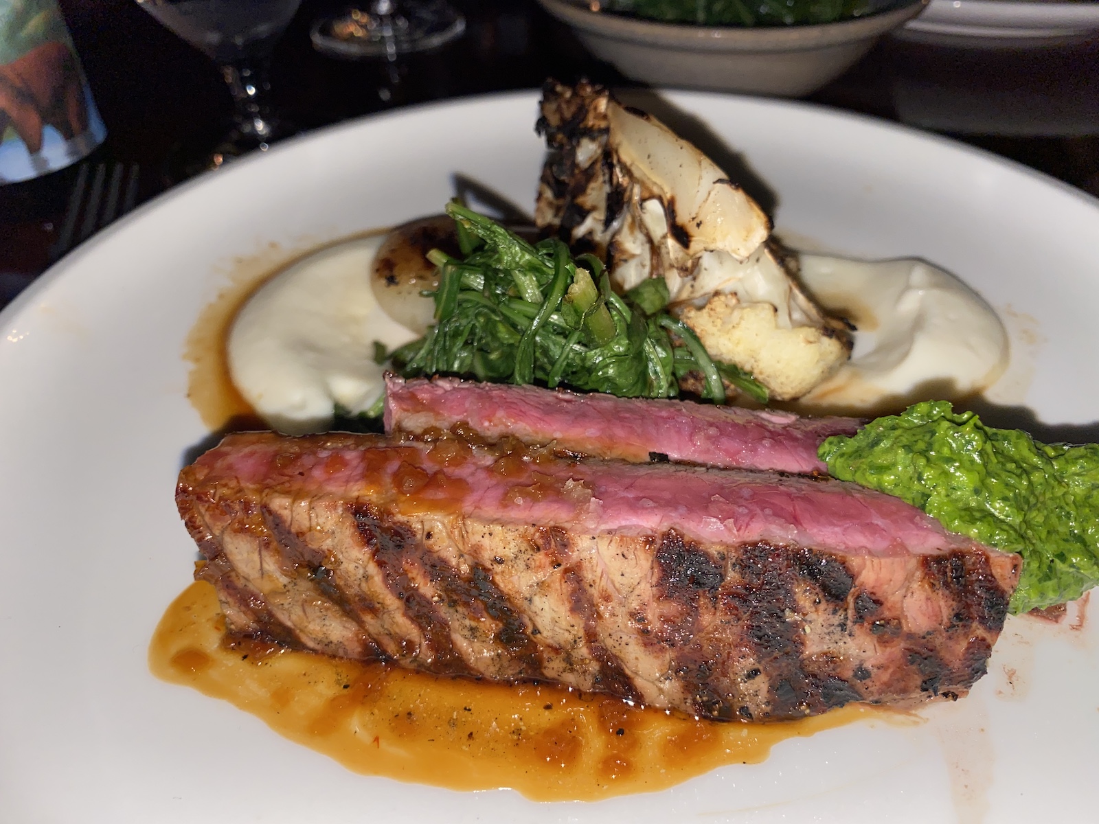 DRY AGED NY STRIP STEAK: Porcini Rubbed, Cauliflower Mash, Roasted Cauliflower, Garden Chimichurri, Greens, Cipollini Demi